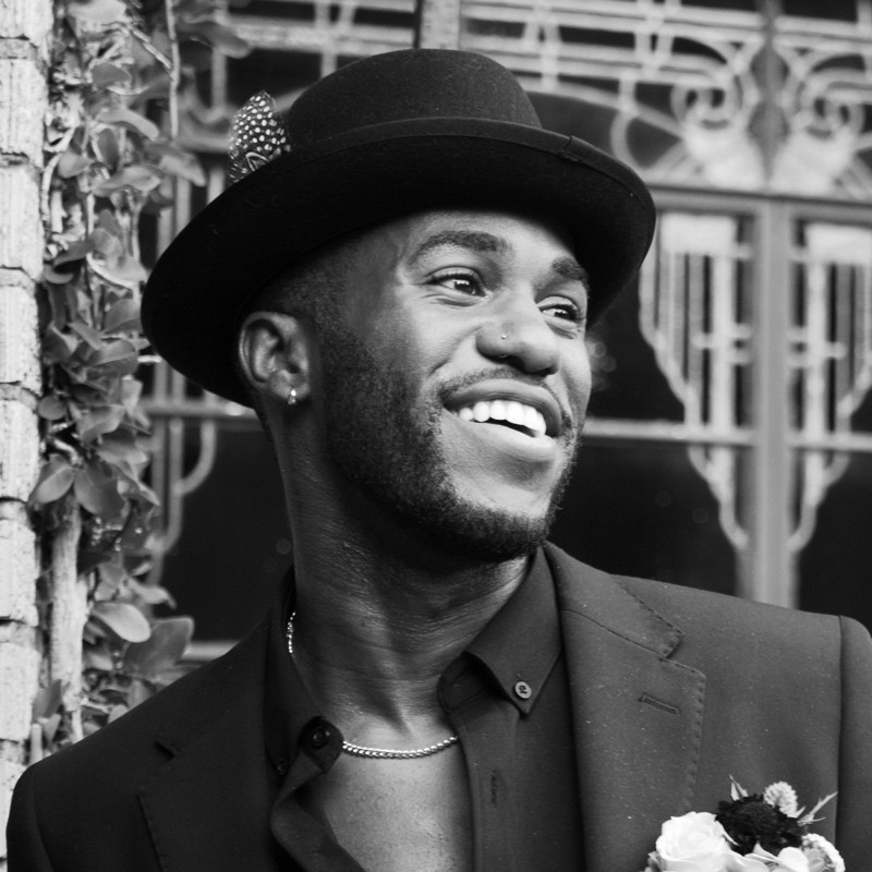 Darnell Walker Jr. smiling in a black hat and blazer